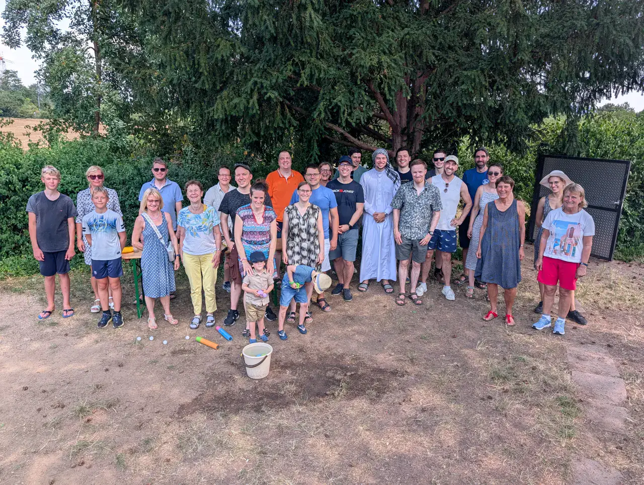Rund dreißig Vereinsmitglieder stehen beim Sommerfest am Ufer eines Sees beieinander